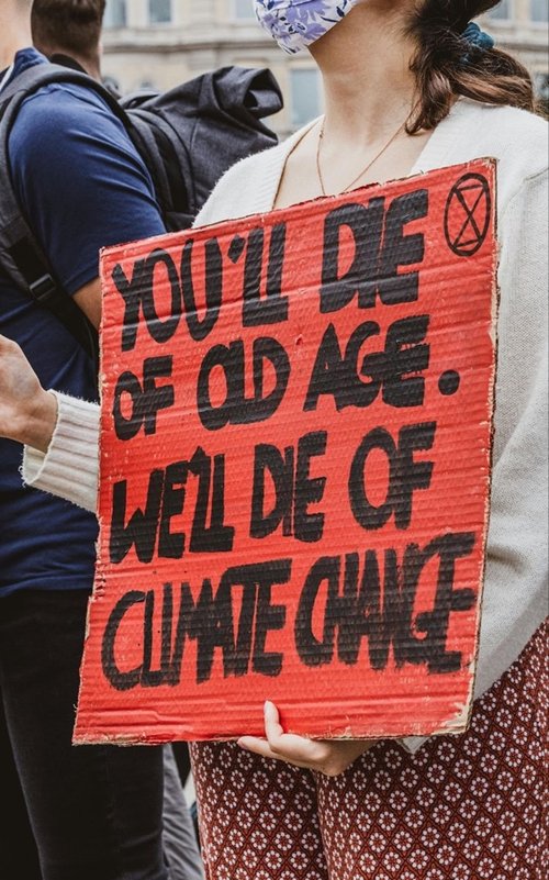 Figuur 1: Een protestbord met de tekst “Jij sterft van ouderdom. Wij sterven door klimaatverandering.” Stockfoto door Kevin Grieve van Pexels.